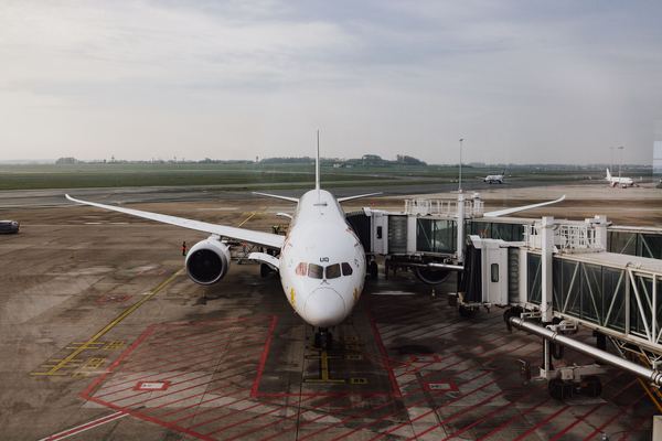A passenger jet parked at a jet bridge on an airport apron.