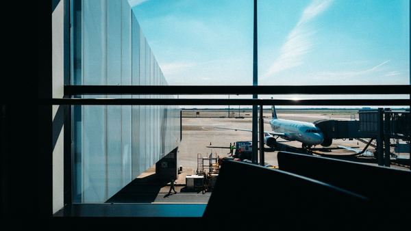 A jet waits at the gate, seen through a dark terminal window.