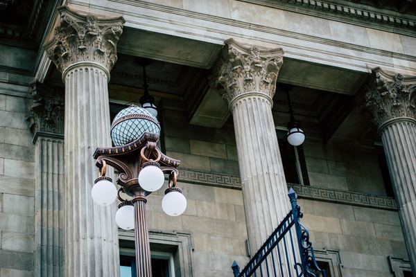 Tall stone columns and an old lamp outside a courthouse.