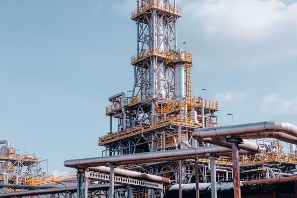 Steel towers and pipes of an oil refinery against the sky.