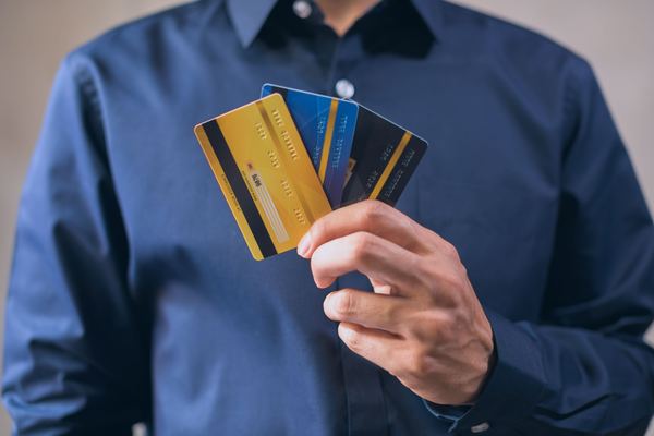 A hand fans out several plain credit cards in front of a blue shirt.