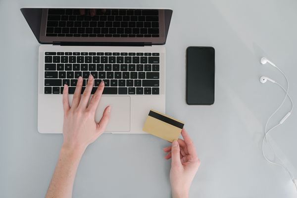 Top-down view of hands at a laptop holding a card next to a phone.