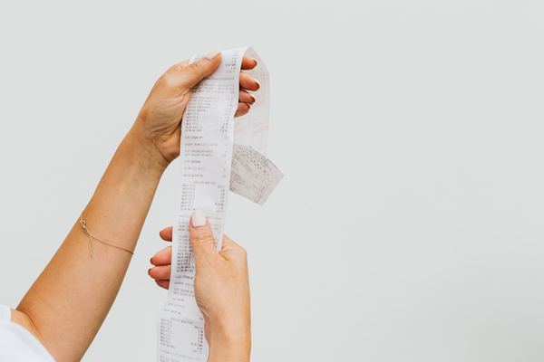 Two hands hold up a long, curling store receipt.