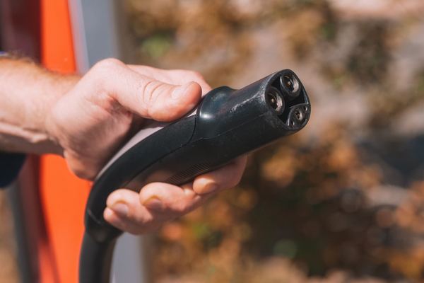 Hand holding an electric car charging plug