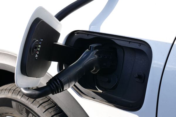 Charging cable plugged into the port of a white electric car