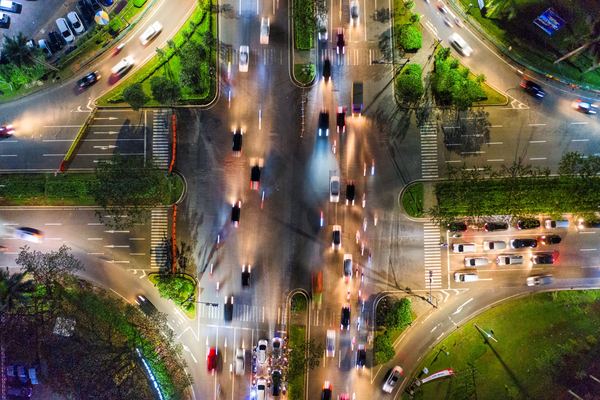 Aerial view of a busy city intersection at night with car light trails