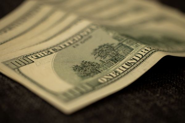The back of a hundred-dollar bill curled in low warm light.