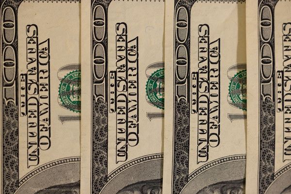 Close-up of the edges of several hundred-dollar bills lined up.