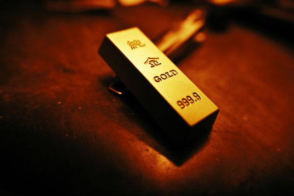 A small gold bar stamped 999.9 glows on a dark table.