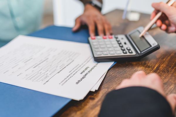 Hands using a calculator over loan documents on a desk