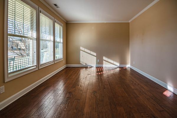 An empty sunlit apartment room with wood floors