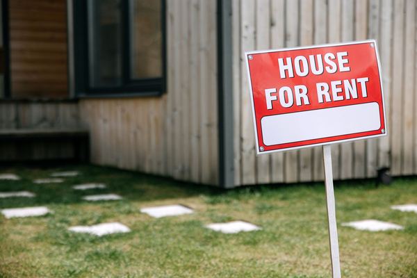 A red House For Rent sign on a lawn in front of a home