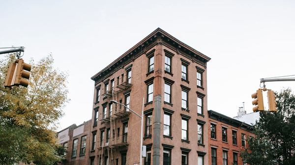 A brick walk-up apartment building on a city street corner