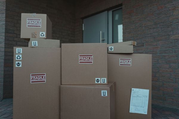 A stack of cardboard shipping boxes outside a front door
