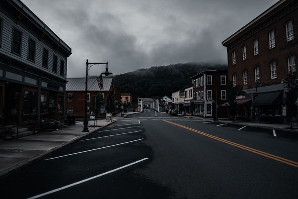 A small-town main street lined with shops under a dark sky