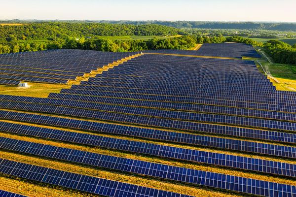 Rows of solar panels covering rolling farmland