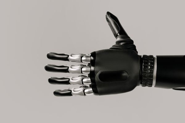 Black robotic hand with metal finger joints against a grey background