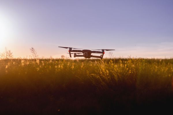 Drone flying low over a field at sunset