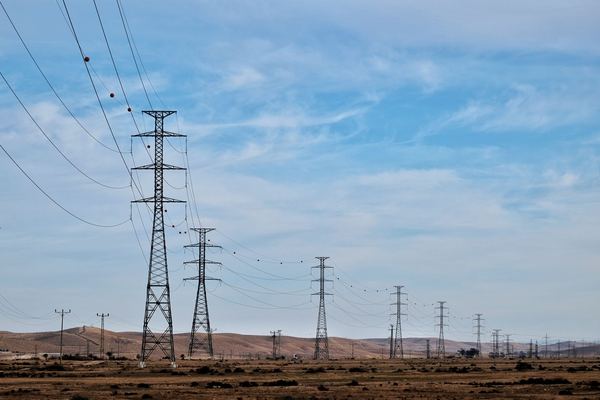 Row of high-voltage transmission towers across a dry plain