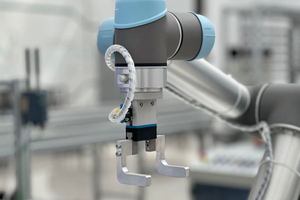 Collaborative robot arm with a metal gripper in a factory
